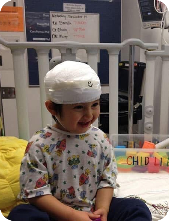 My son sitting up in a hospital bed during an EEG, his head wrapped.